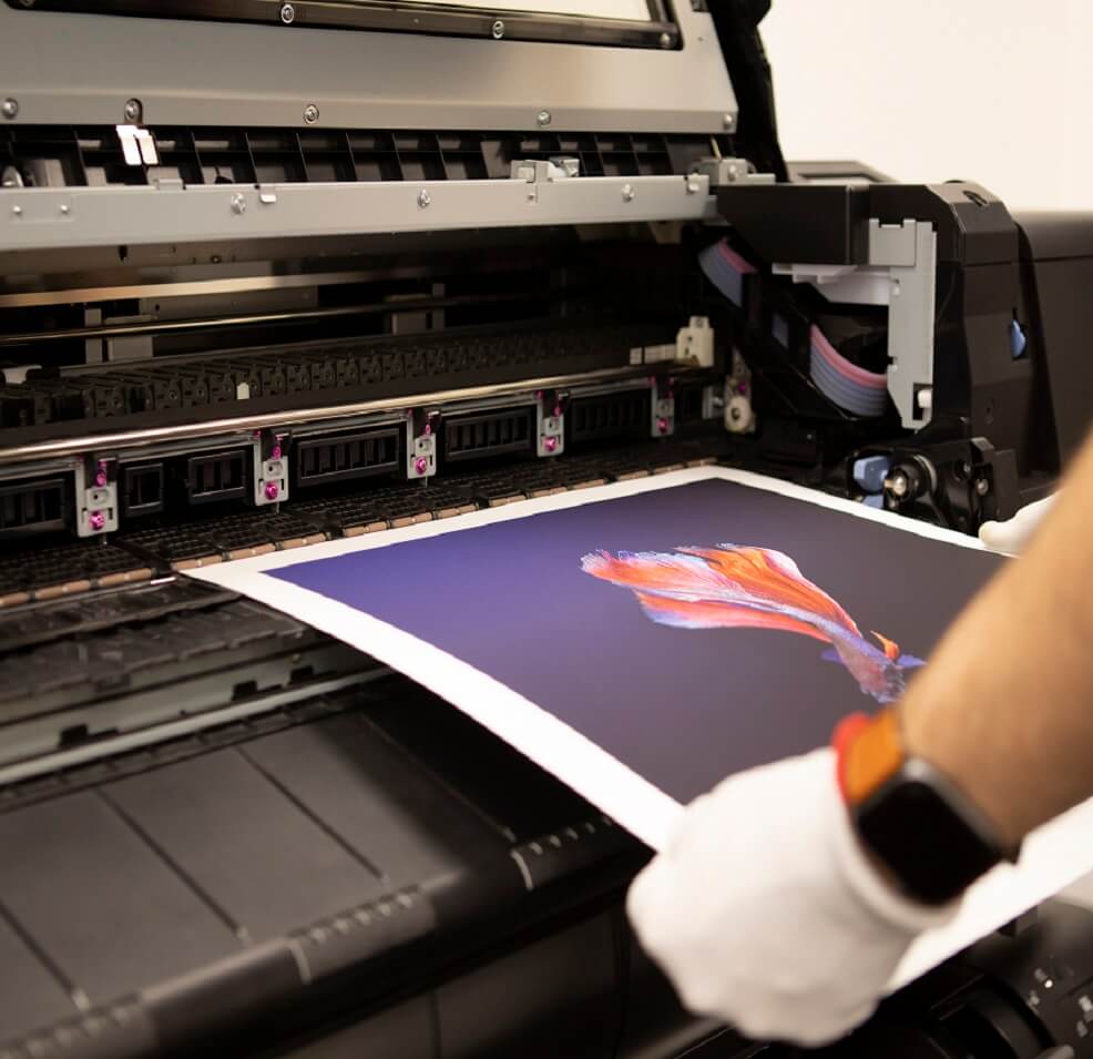 a Man's and feeding a photograph through a printer, wearing a glove